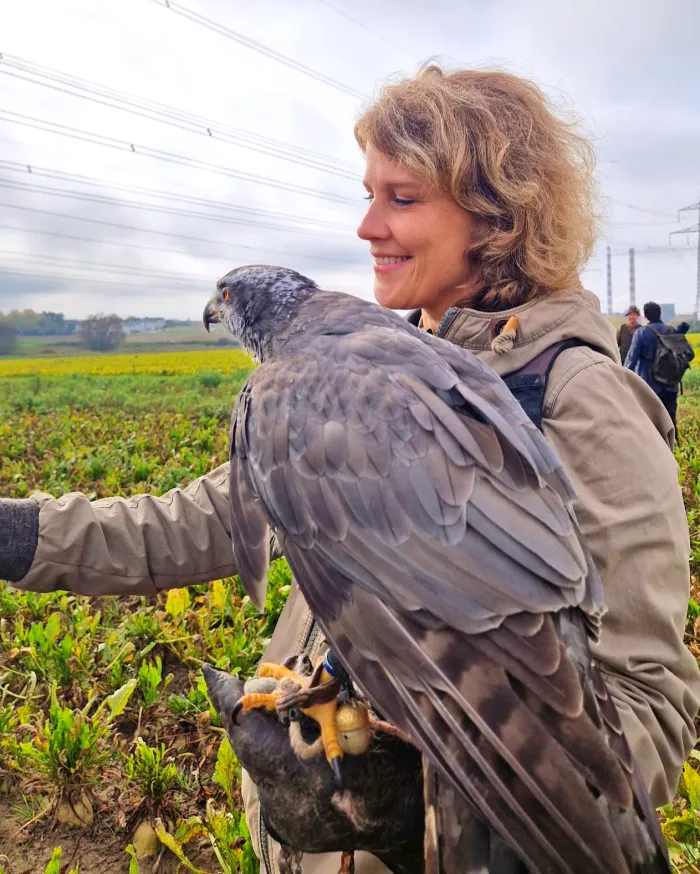 Elsa Lößner auf einem Feld, auf ihrem Handschuh sitzt ein Habicht